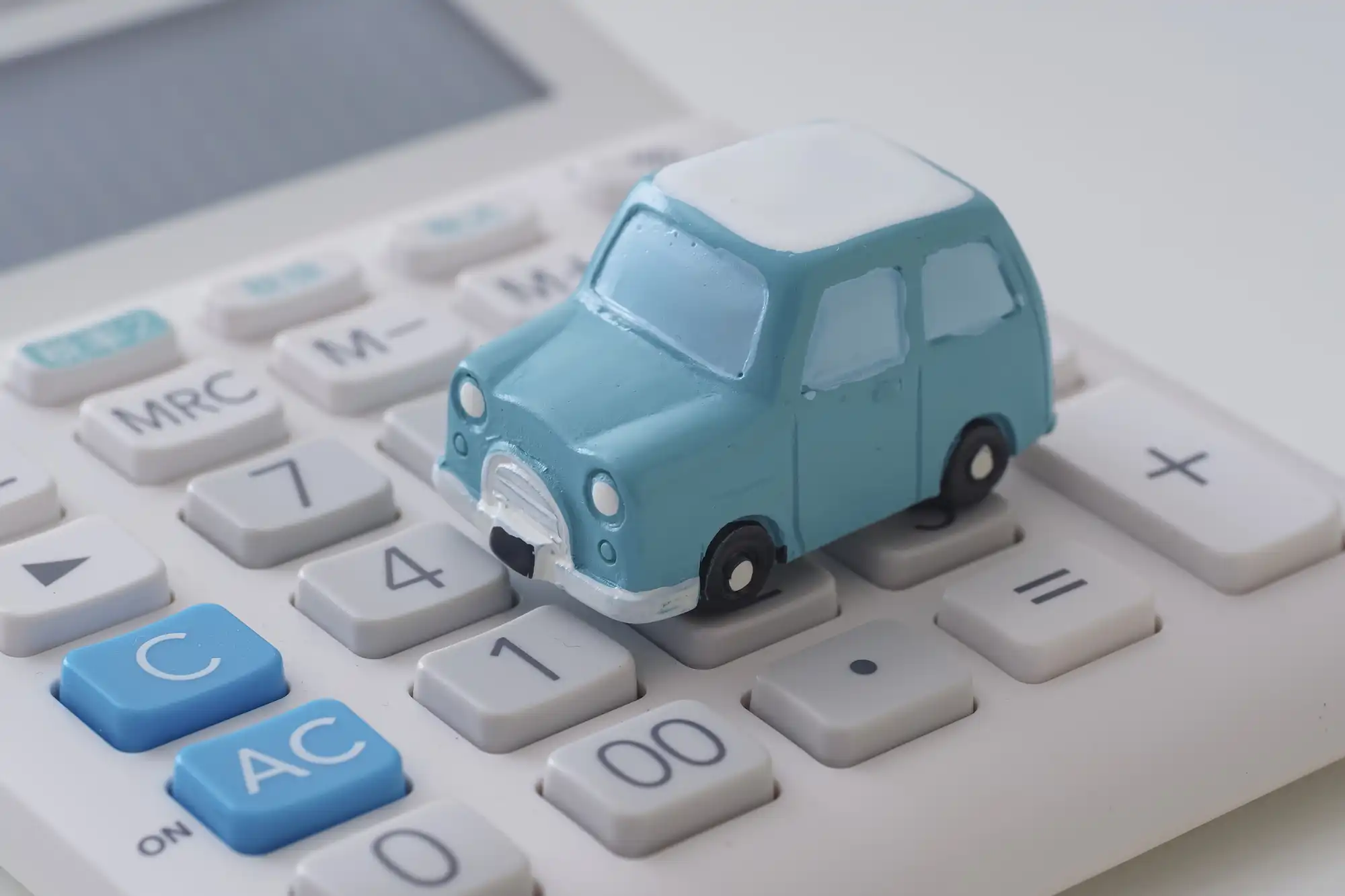電卓の上に青の車の模型が置かれている