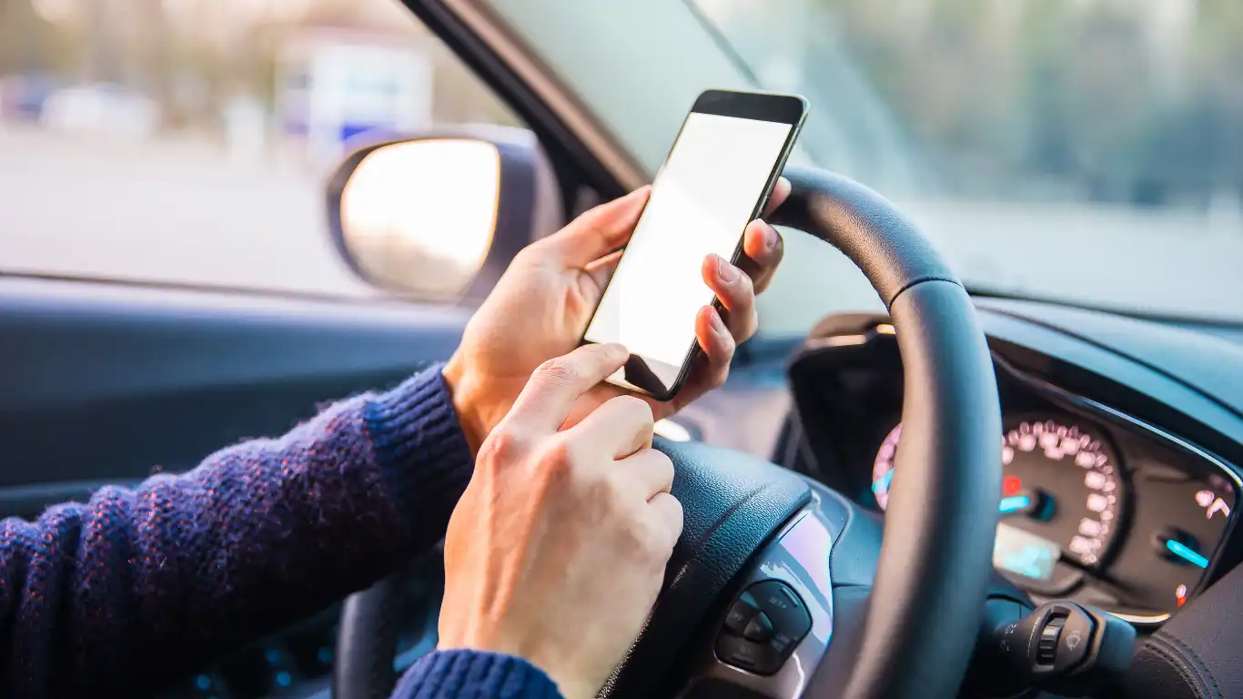 止まった車の運転席でスマホを操作している