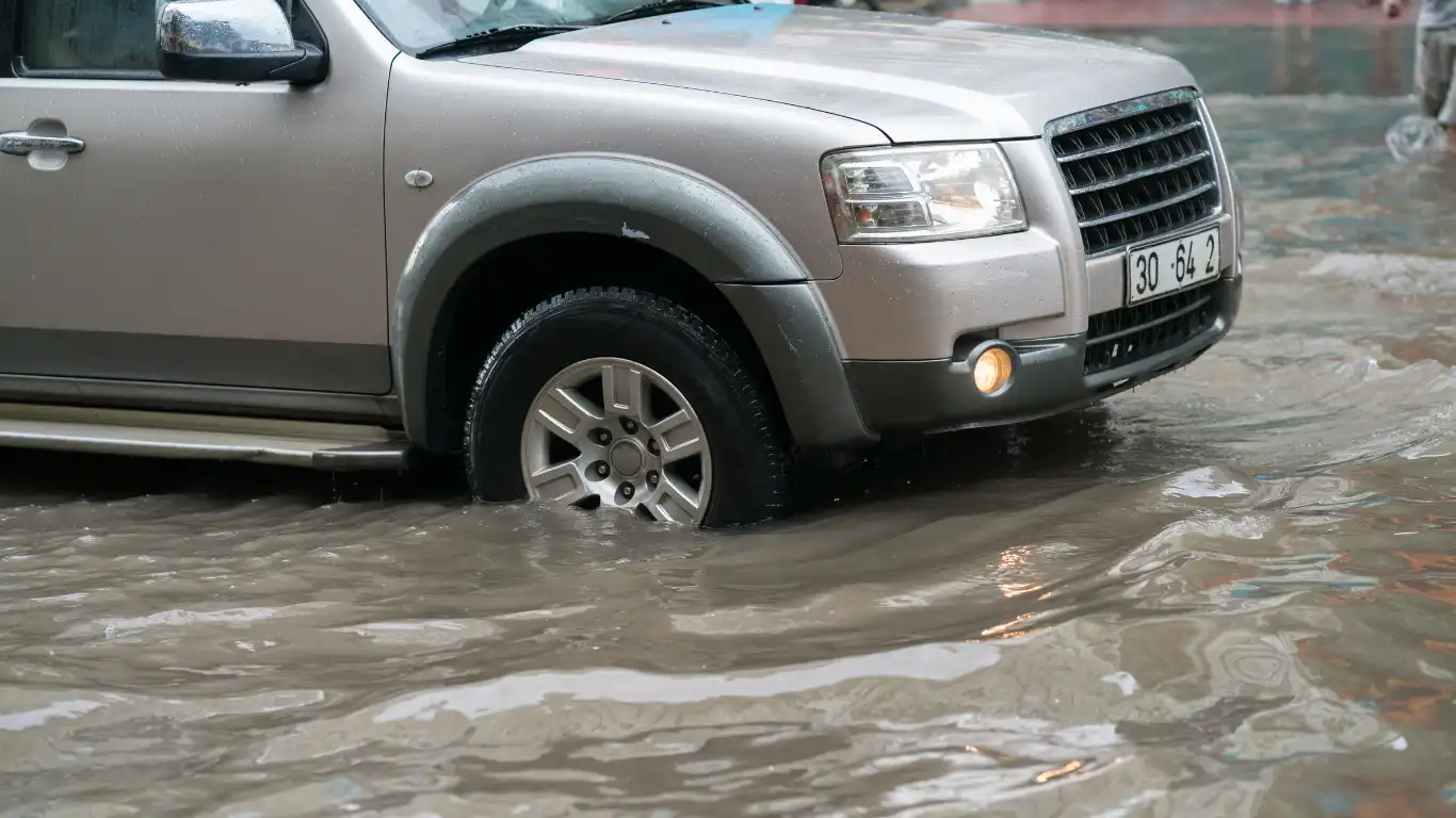 冠水した道路を走るゴールドの車