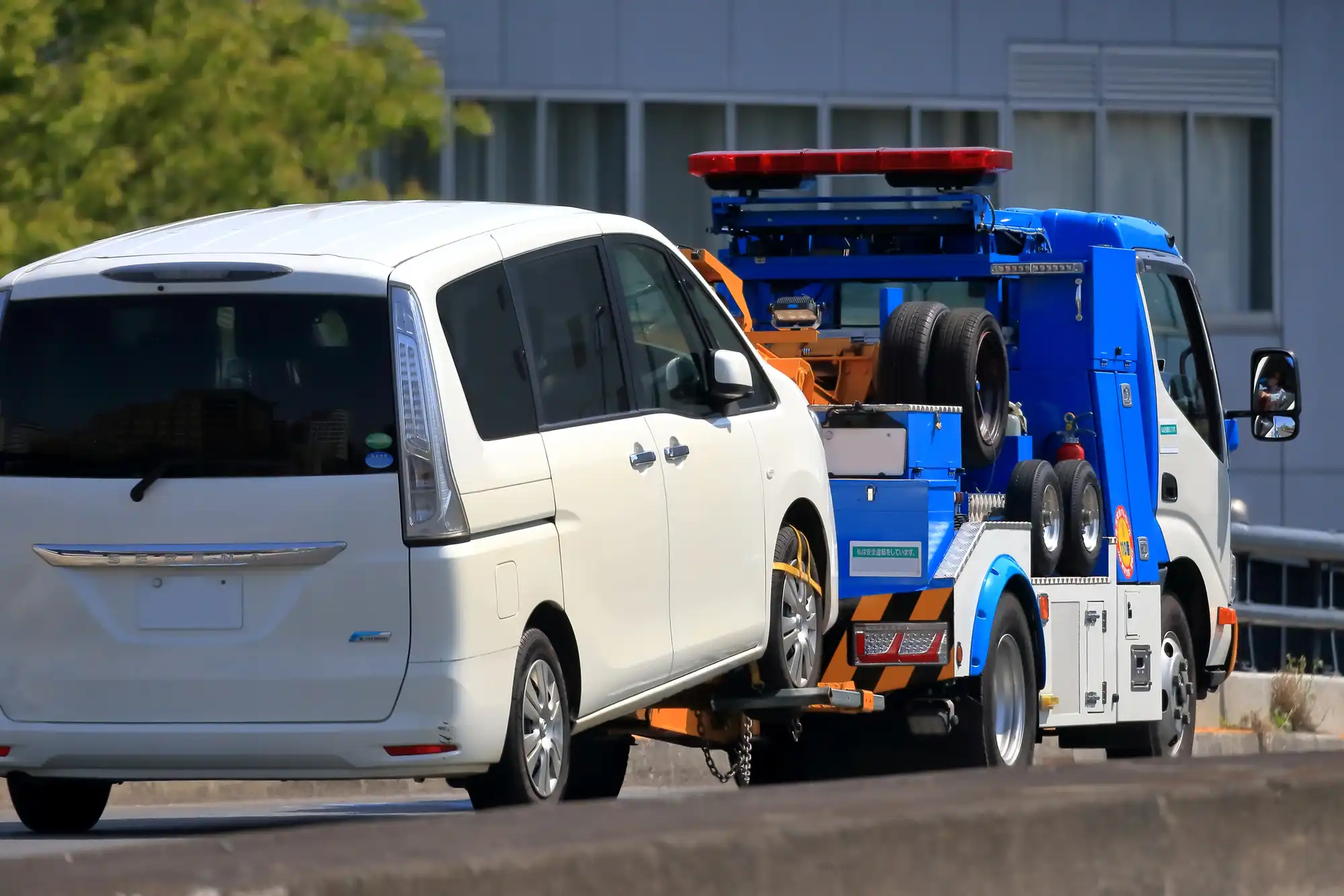 レッカー移動される白のワンボックスカー