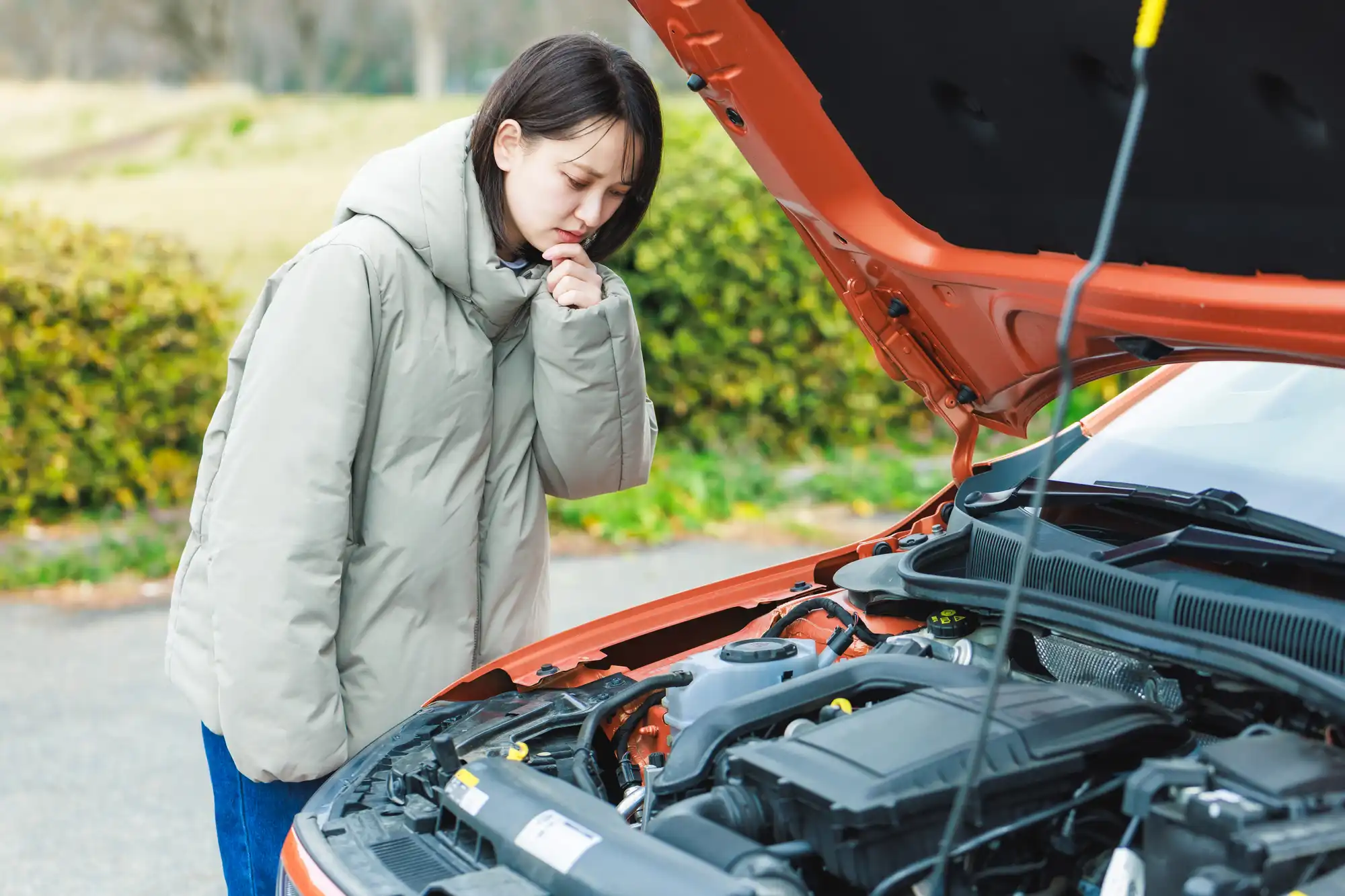 ボンネットを開けて不安そうに見る女性