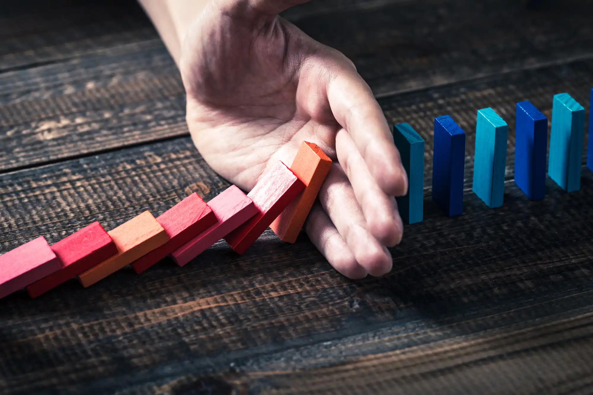 ドミノ倒しを手で遮っている