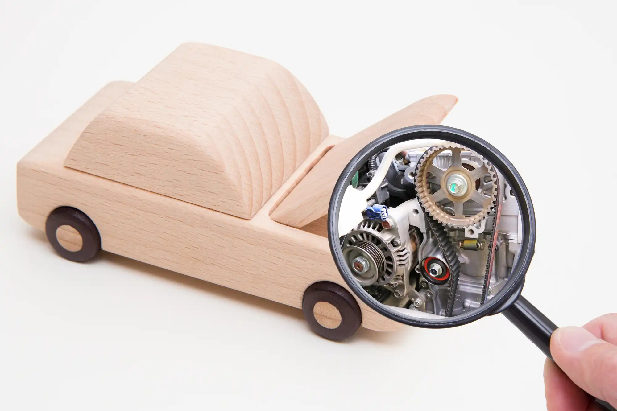 ボンネットを開けた車の模型を虫眼鏡で見ている