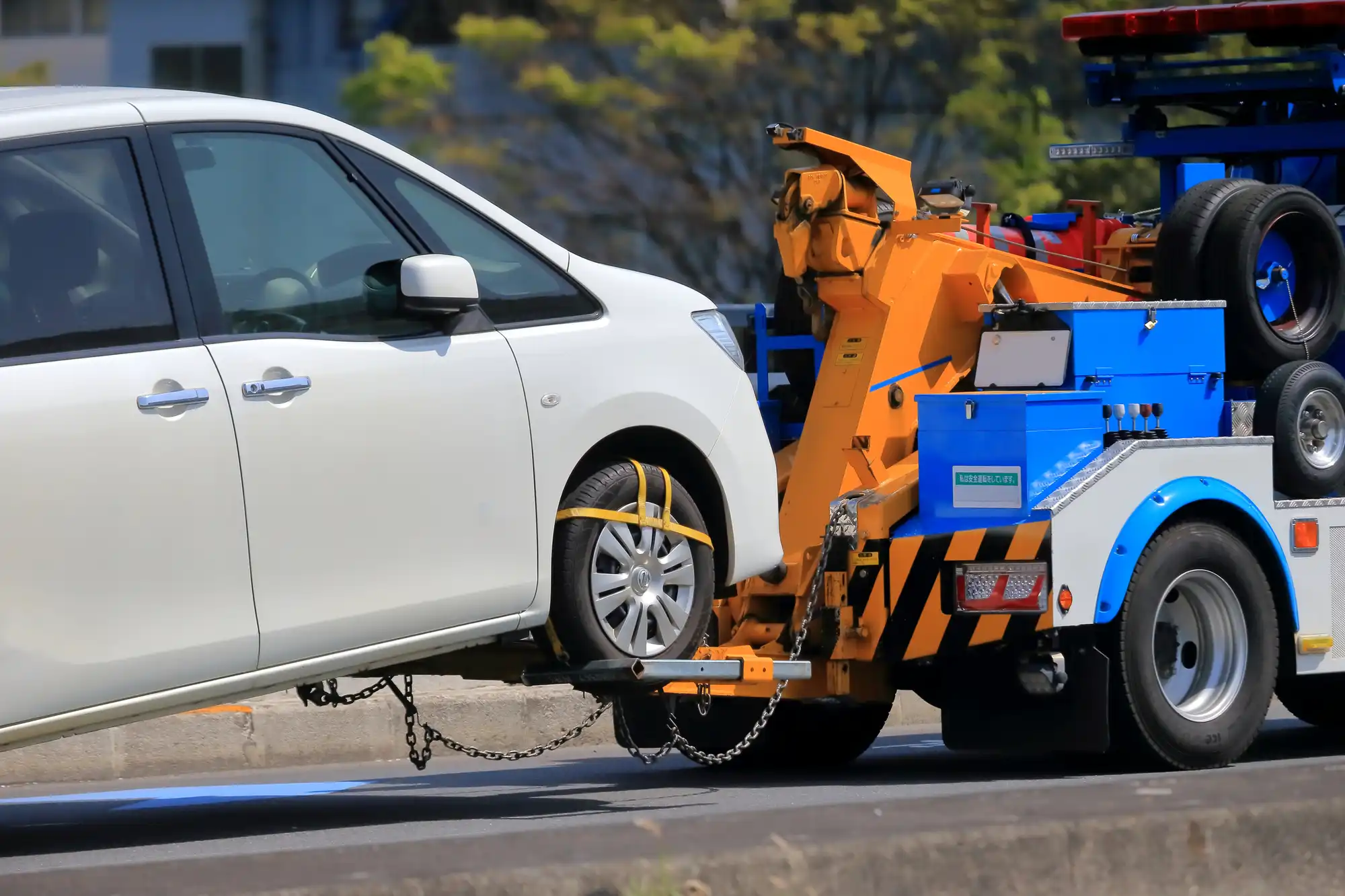レッカー移動される白いワンボックスカー