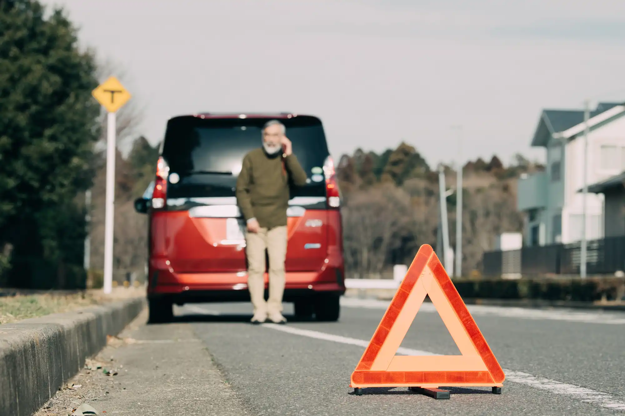 道に三角表示板を置いて赤い車を止めている