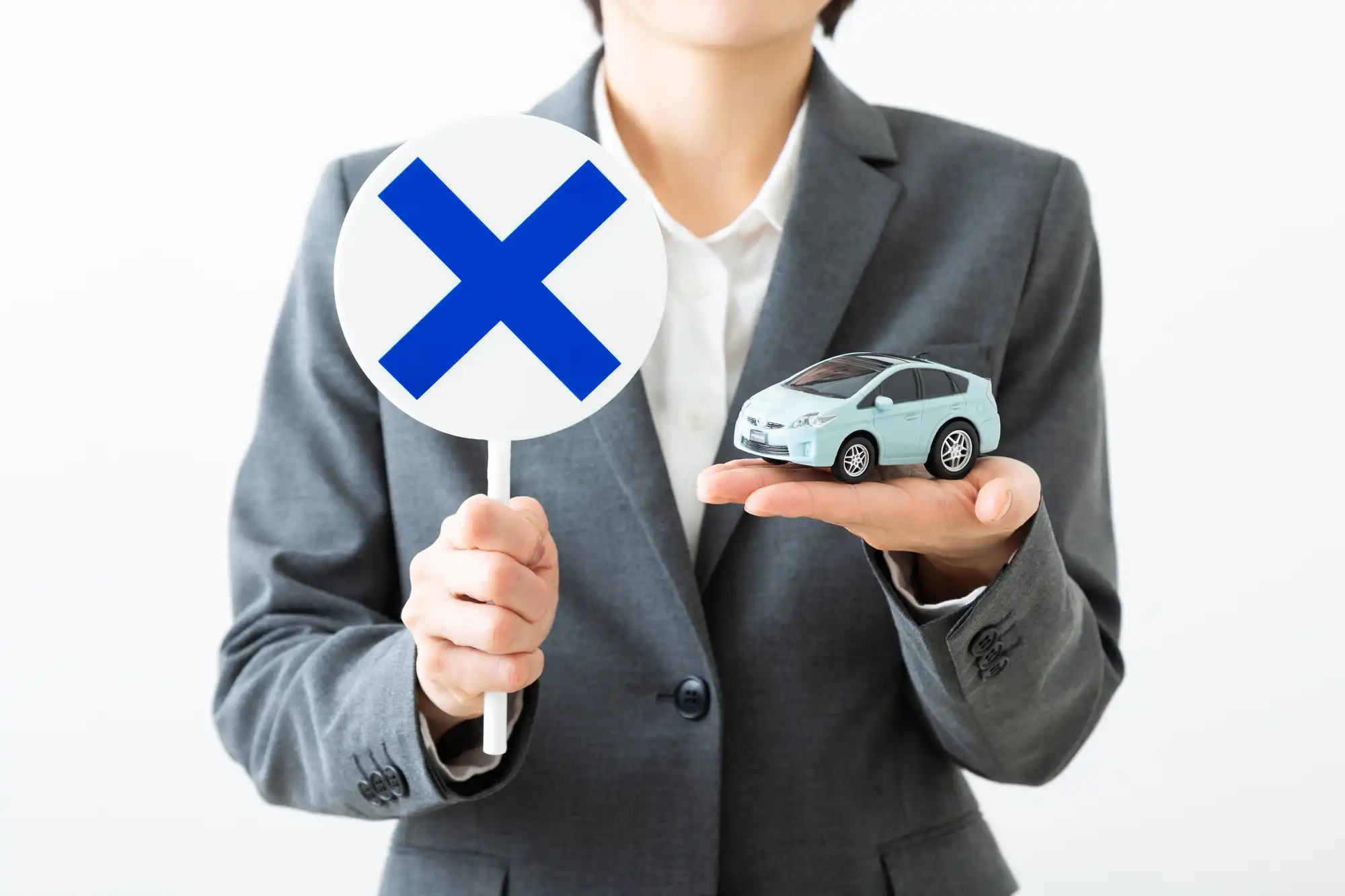 バツの手札とミニカーを持つ女性