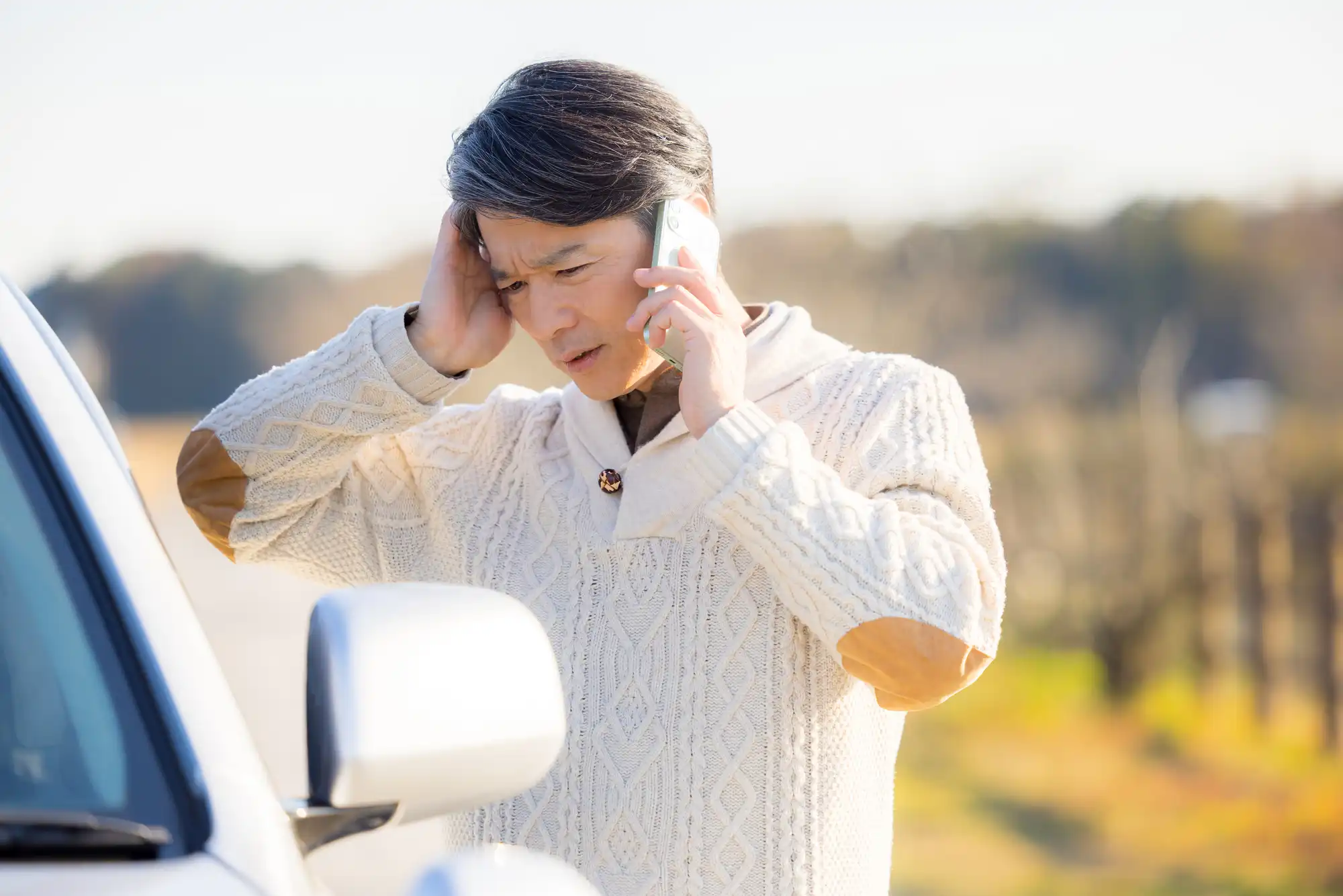 困った表情で電話する男性