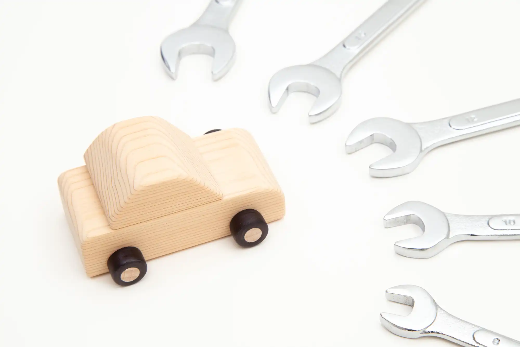 木でできたおもちゃの車の周りにスパナを置いている